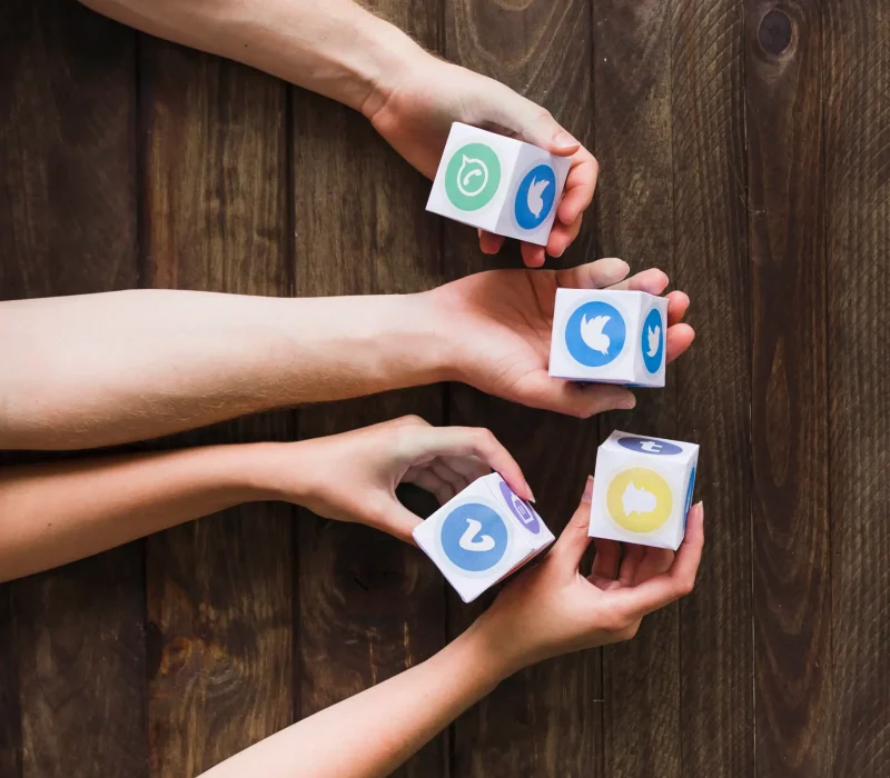 man-woman-holding-blocks-social-media-icons-wooden-table